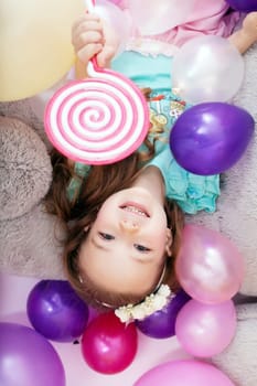 Top view of cheerful little girl posing with balloons