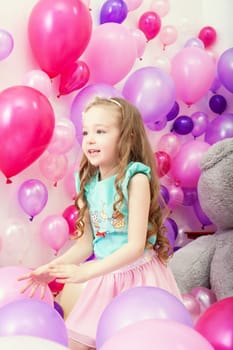 Studio shot of cute little girl playing among balloons