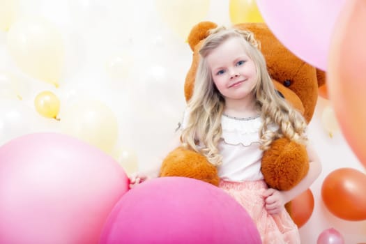 Image of smiling blonde girl playing with teddy bear