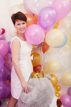 Charming middle-aged model posing with bunch of balloons