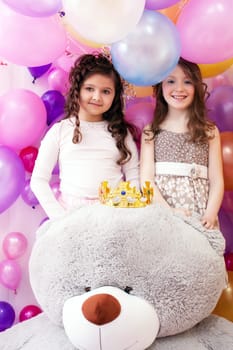 Portrait of two smiling cute sisters and big teddy bear