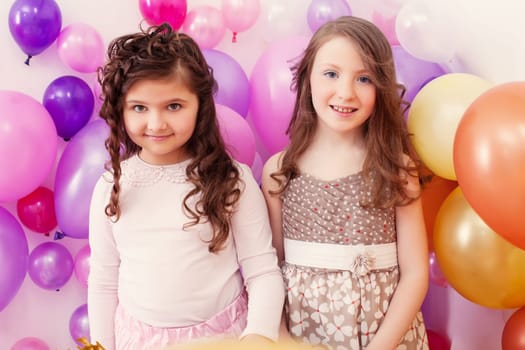 Image of two merry girlfriends posing on balloons backdrop