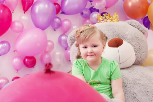 Neat little girl posing in studio with balloons, close-up