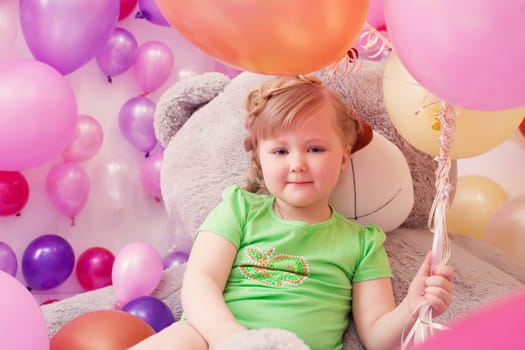 Image of cute little girl posing with big teddy bear in playroom