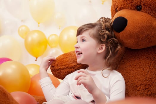 Joyful little girl posing hugging plush bear, close-up
