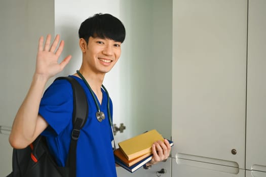 Smiling asian man medical student standing at lockers in campus. Medical internship , education and learning concept.