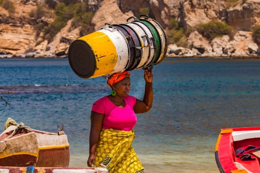A woman carries some empty vats effortlessly on her head, Santiago Island, Cape Verde Islands in the Atlantic Ocean