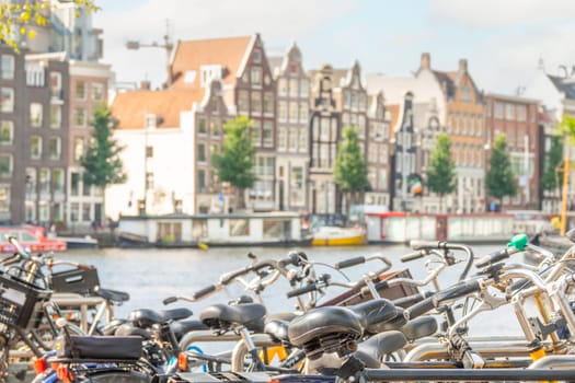 Netherlands. Summer day in Amsterdam. A lot of bicycles on the canal embankment against the background of typical buildings in defocus