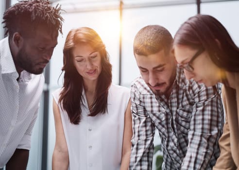 The concept of cooperation and brainstorming. Portrait of interracial friends gathered together, standing around a table in a classroom surrounded by books