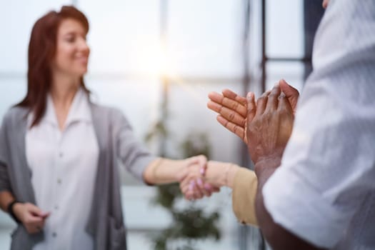 Two professional business people shaking hands in an office lobby