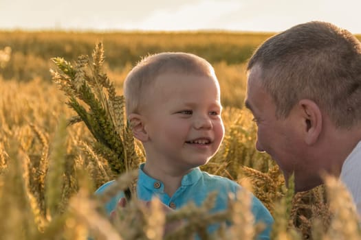 Dad and his little son are having fun walking in a field with ripe wheat. Grain for making bread. the concept of economic crisis and hunger