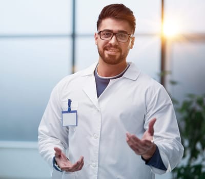 Doctor middle man, medical worker, makes a hand gesture inviting patients.