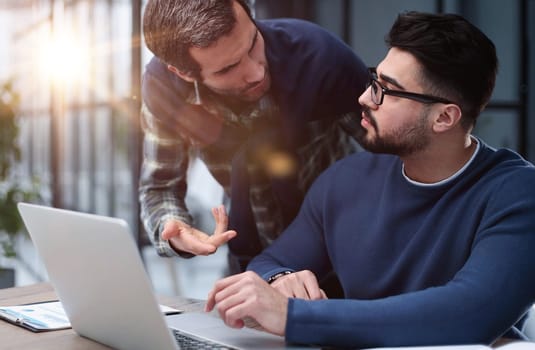 two male colleagues are talking at the table in the office. joint business concept