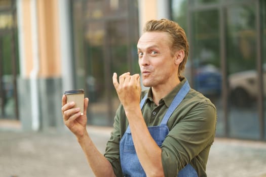 Waiter presenting delicious and tasty cup of coffee in paper cup to-go. With smile on face, waiter highlights tempting aroma and flavor of coffee, enticing viewer to indulge in delightful beverage. High quality photo