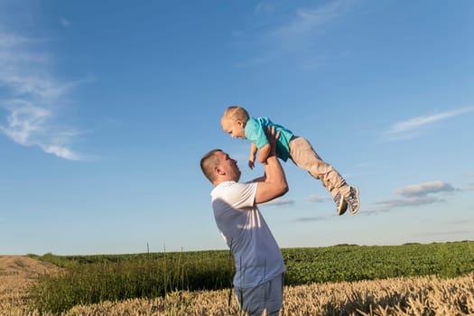 Dad and his little son are having fun walking in a field with ripe wheat. Grain for making bread. the concept of economic crisis and hunger