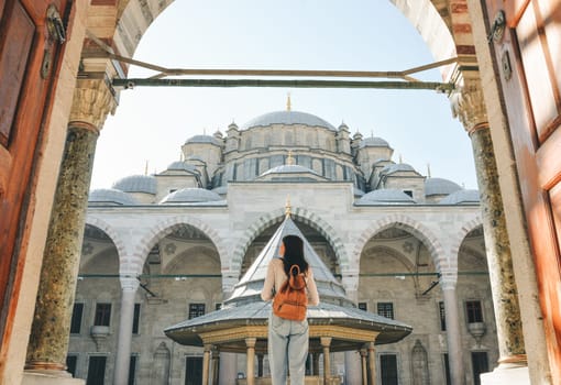 A young female traveler with a backpack on her back walks towards the Fatih Mosque in Istanbul.