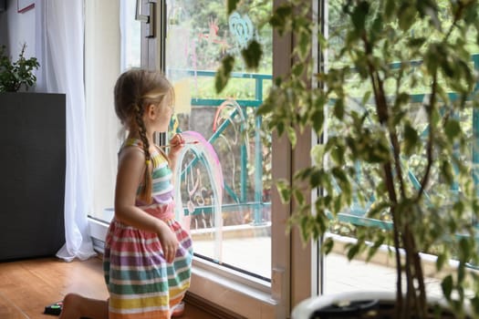 Girl draws a rainbow on the window selective focus