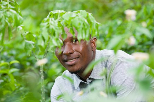 Close up of young man sitting alone behind a bush, breathe the natural area and contemplate the forest