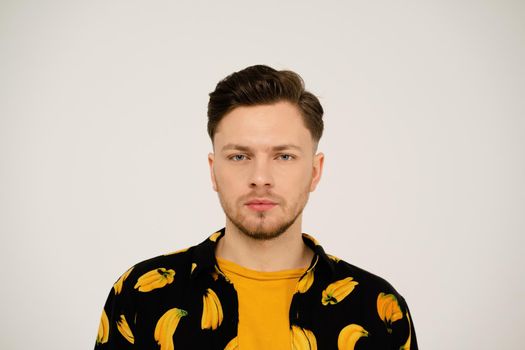 Serious look on face of handsome man in dressed banana shirt and yellow t-shirt under looking at camera. Isolated on white background. Close up shot.