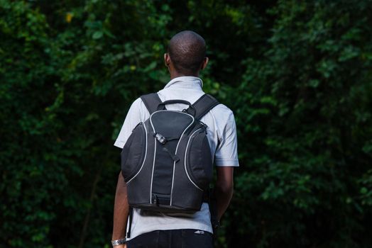 young man in black jeans backpack and goes to the forest.