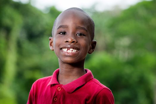Close Up portrait of little cute funny boy looking at camera while smiling while playing outdoors on hot summer day. Horizontal color photography.