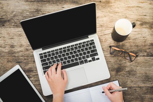 Work concept. Clipboard in women hands. Laptop and cup of tea on wooden table