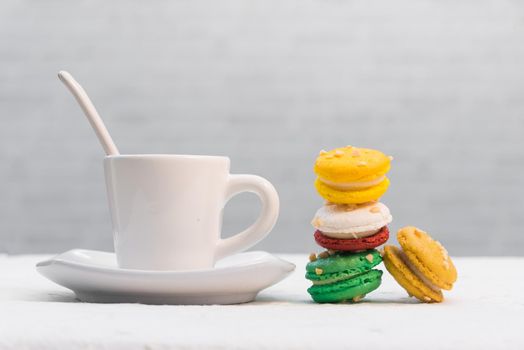 colourful french macaroons with cup of coffee on white background