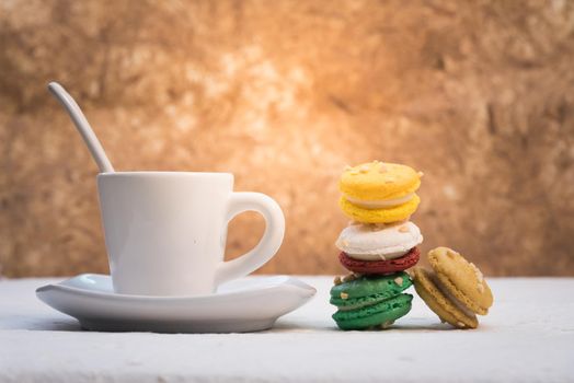 colourful french macaroons with cup of coffee on white background