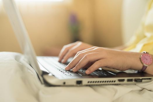 young woman using laptop in bedroom at home