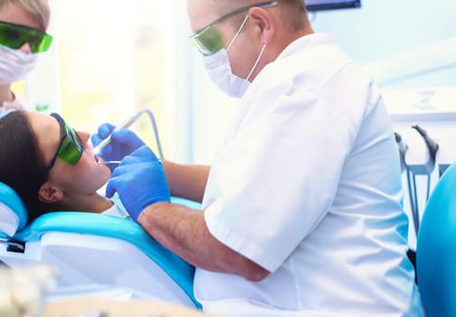 Man dentist working at his patients teeth.