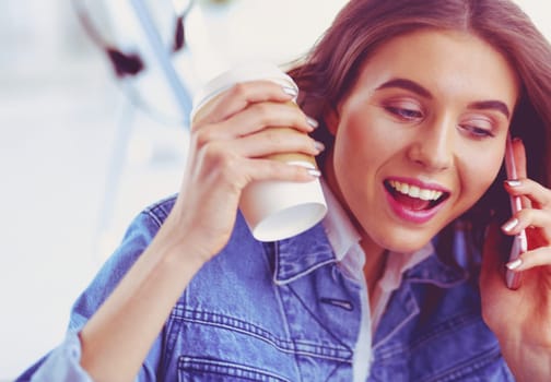 Young woman at cafe drinking coffee and talking on the mobile phone