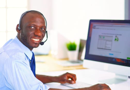 African american businessman on headset working on his laptop.