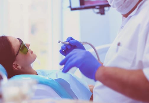 Beautiful senior woman at dentist having dental treatment at dentist's office.