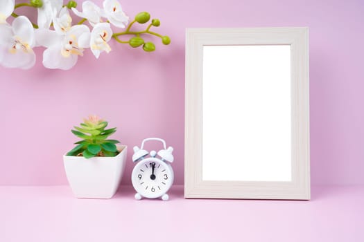 Blank picture frame and alarm clock on pink color background with copy space and clipping path for the inside.