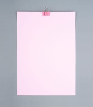 Pink color binder clip and blank pink paper on gray color background,