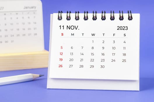 November 2023 Monthly desk calendar for 2023 year with pencil on purple background.