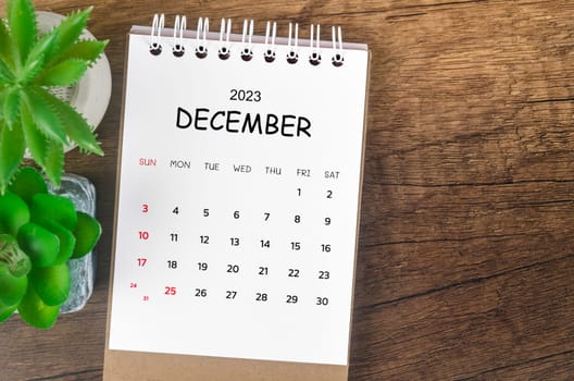 December 2023 desk calendar for 2023 on wooden background.