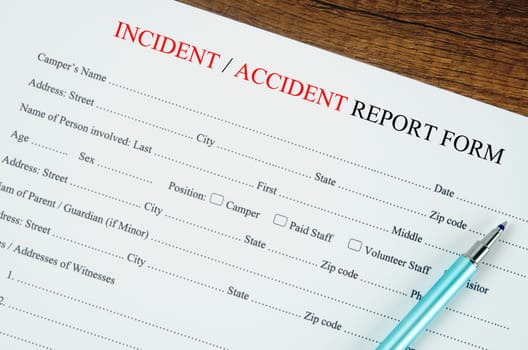 Accident report form with pen on wooden background.