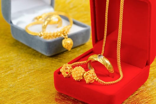 Gold necklace and heart shape pendant with ring on red velvet box.