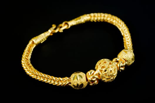 Gold bracelet on black background.