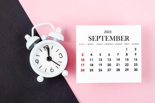September 2023 Monthly calendar year with alarm clock on pink colour background.