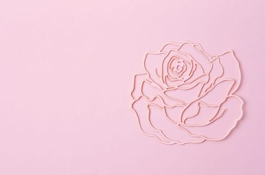 Carve of paper pink rose flower on a pink cardboard background.