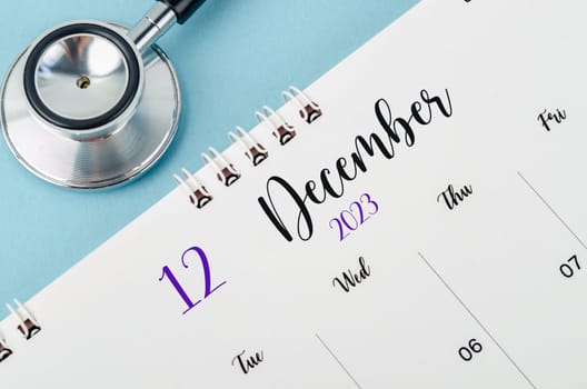 December 2023 deskcalendar and medical stethoscope medical on blue background, schedule to check up healthy concepts.