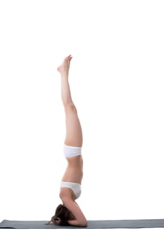 Side view of slender young woman doing handstand
