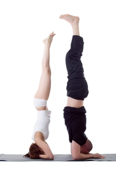 Couple of flexible yoga trainers doing handstand
