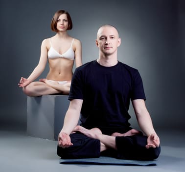 Studio shot of meditating yoga trainers, on gray backdrop