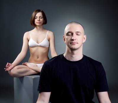 Yoga studio. Meditating trainers posing on gray backdrop