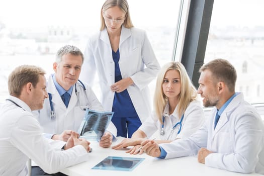 Healthcare, medical and radiology concept - group of doctors looking at x-ray