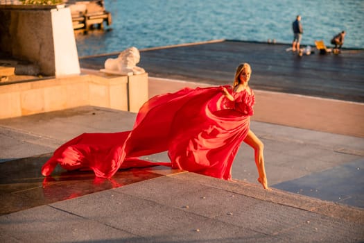 Sunrise red dress. A woman in a long red dress against the backdrop of sunrise, bright golden light of the sun's rays. The concept of femininity, harmony