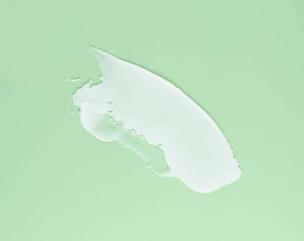 Smear of white cream for face and body on a green background